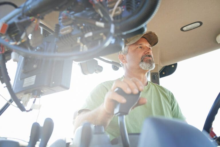 Farmer operating tractor controls inside cabin