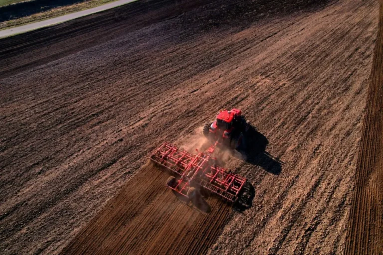 Aerial view of red tractor plowing field